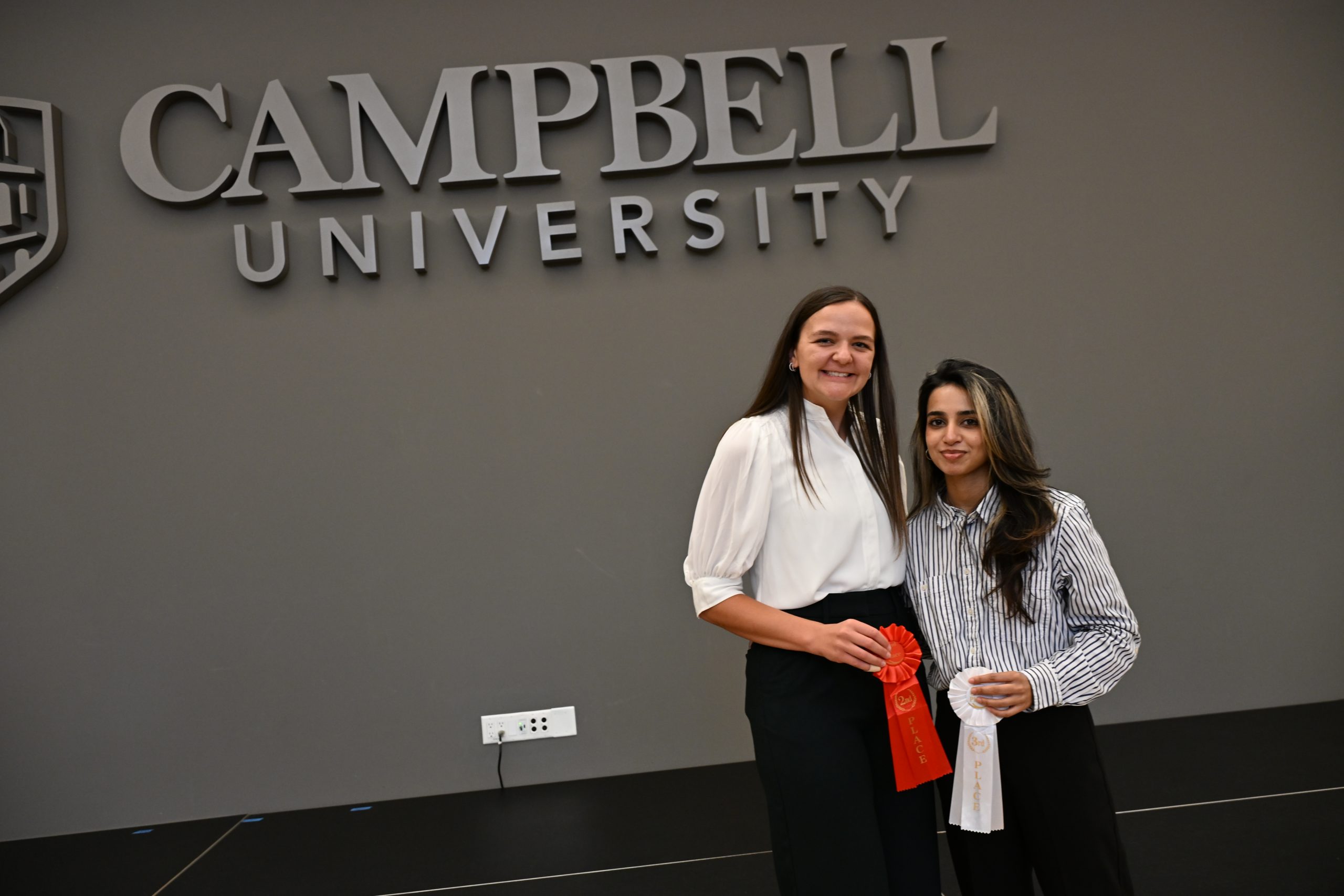Two female students holding award ribbons
