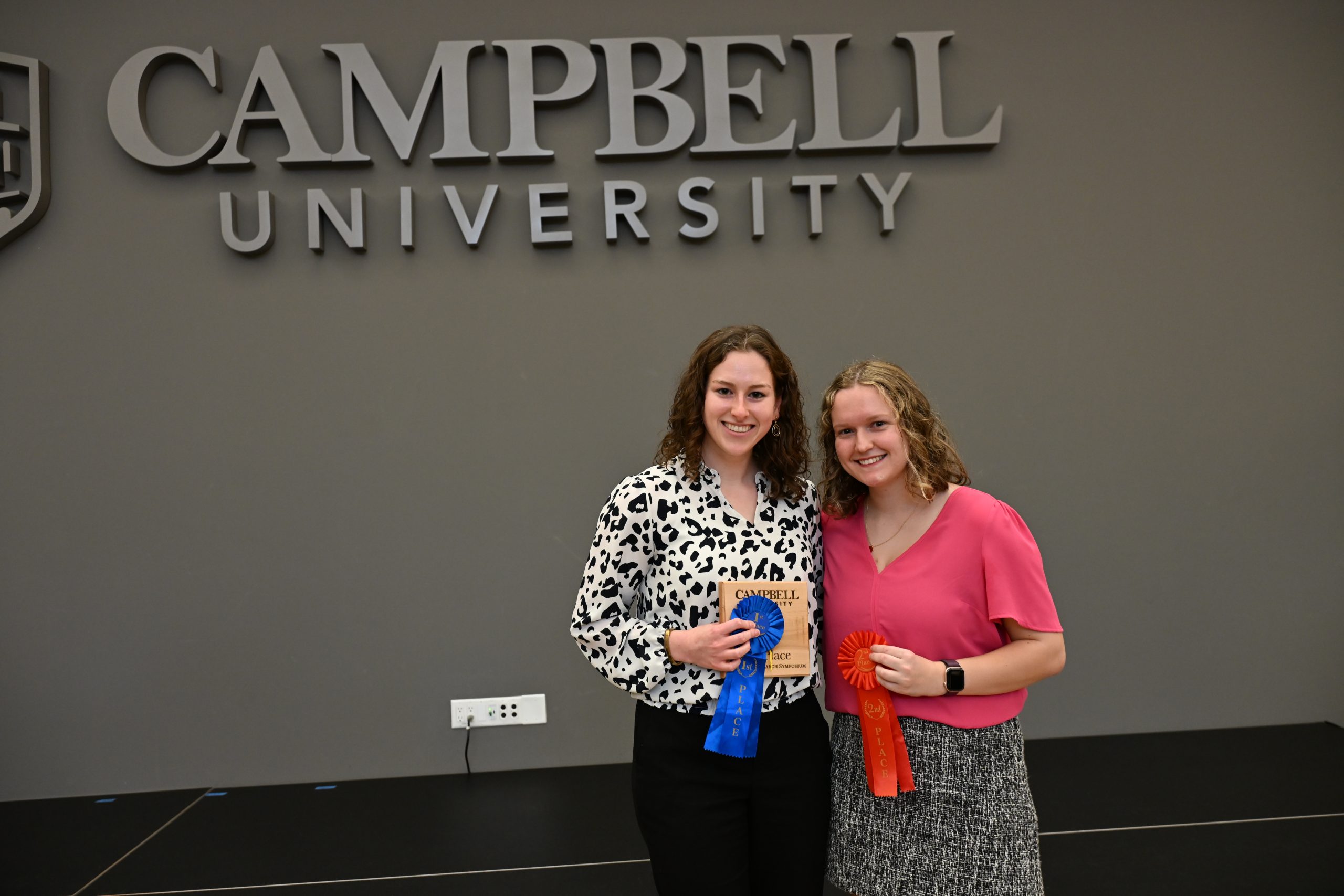 two female students holding award ribbons