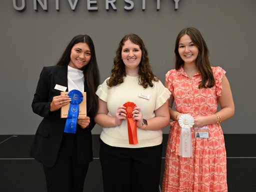 Group of professionally dressed female students holding award ribbons