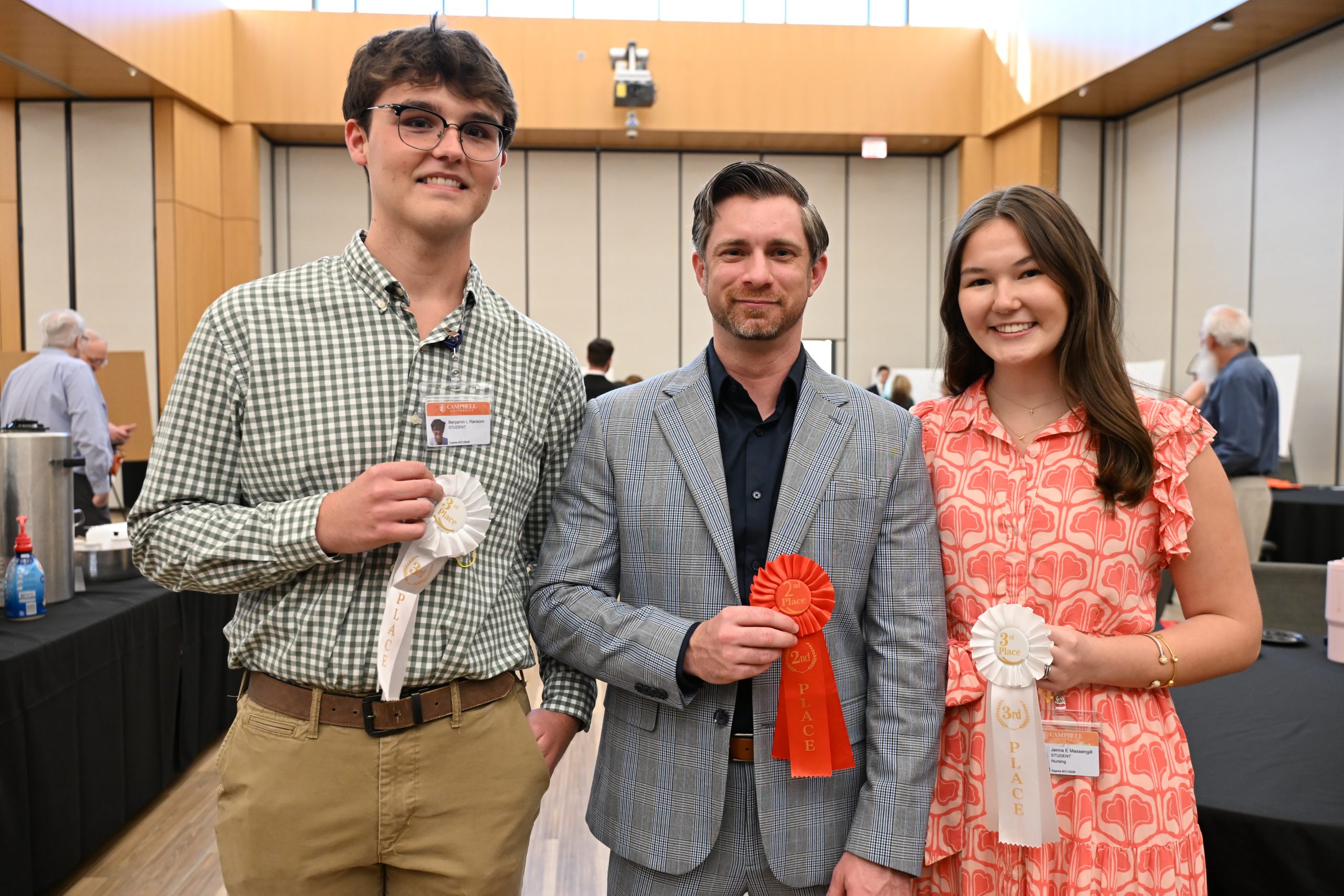 Two male and one female student holding award ribbons