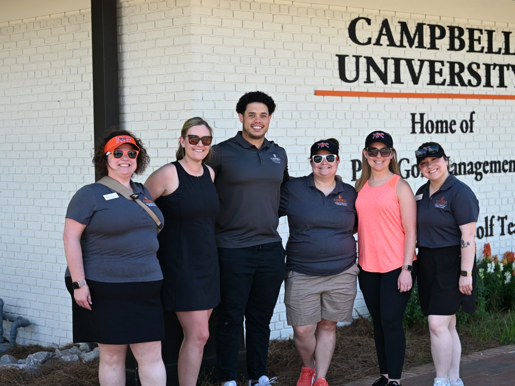 Five females and one male volunteer stand together