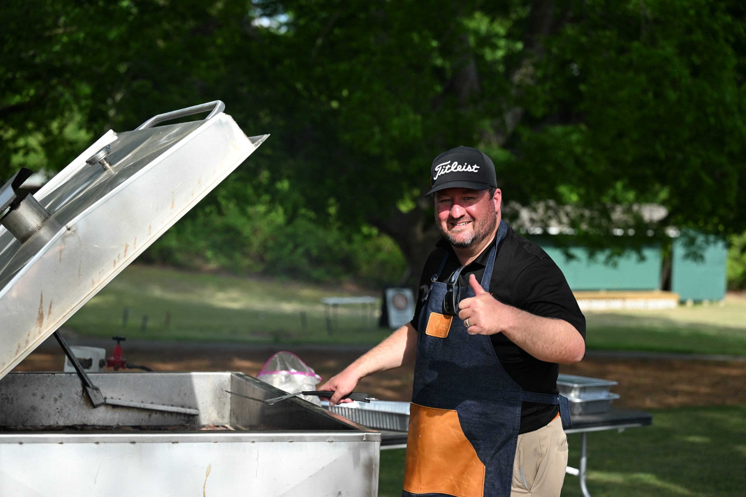 Male volunteer grilling steaks with thumbs up