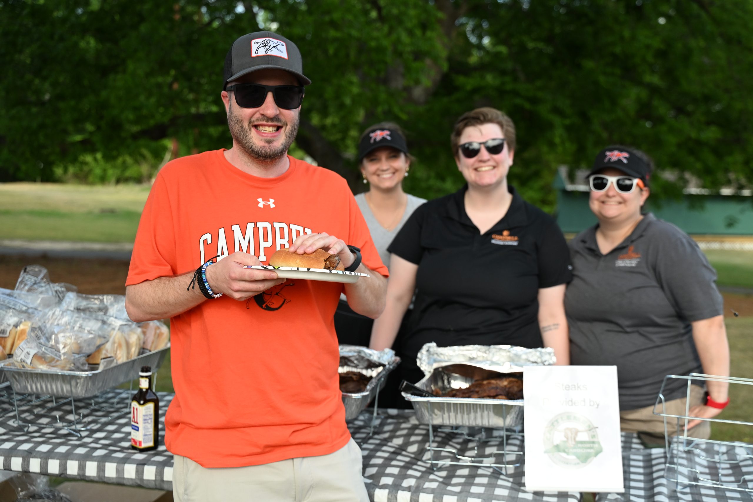 Male golfer in Campbell shirt holding a steak sandwich