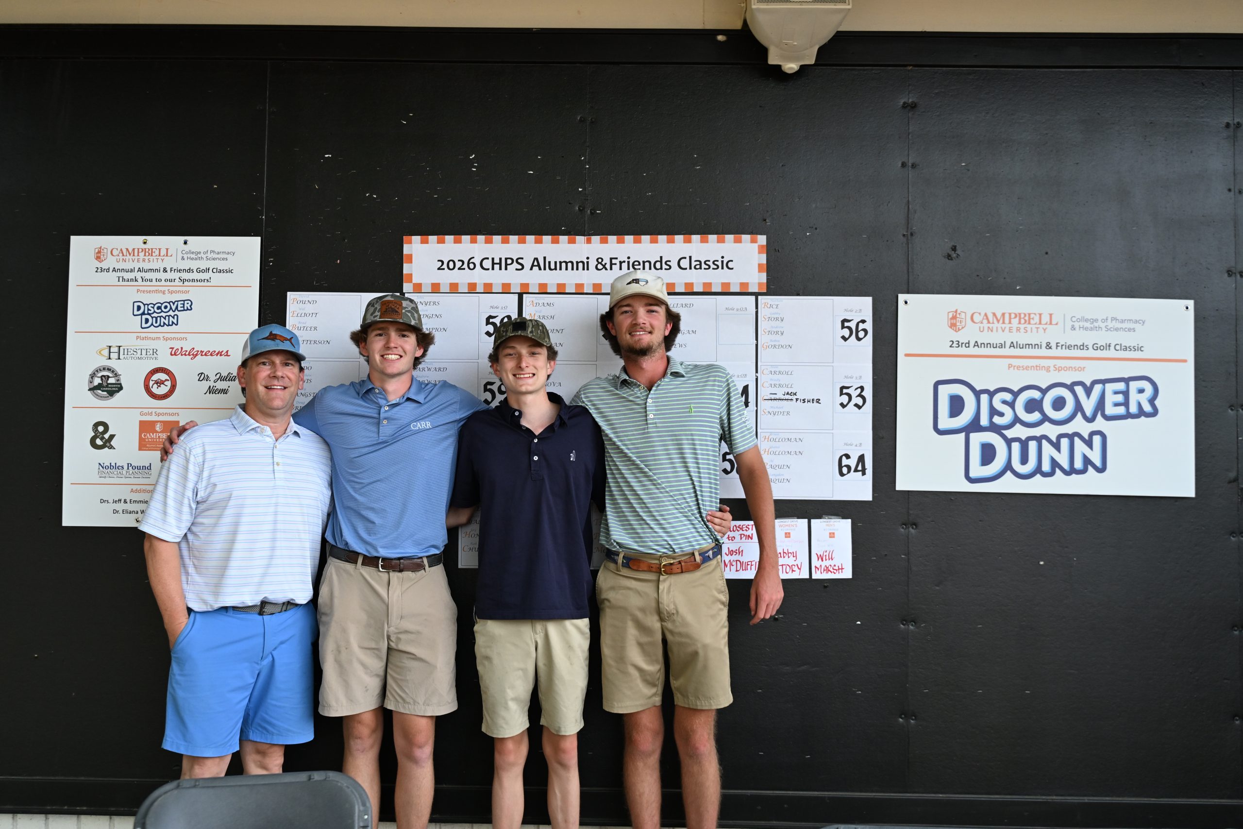 Four male golfers on the winning team stand with the score sheets