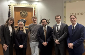 Photo of four Campbell Law trial advocates and their alumni coaches posing in a courtroom