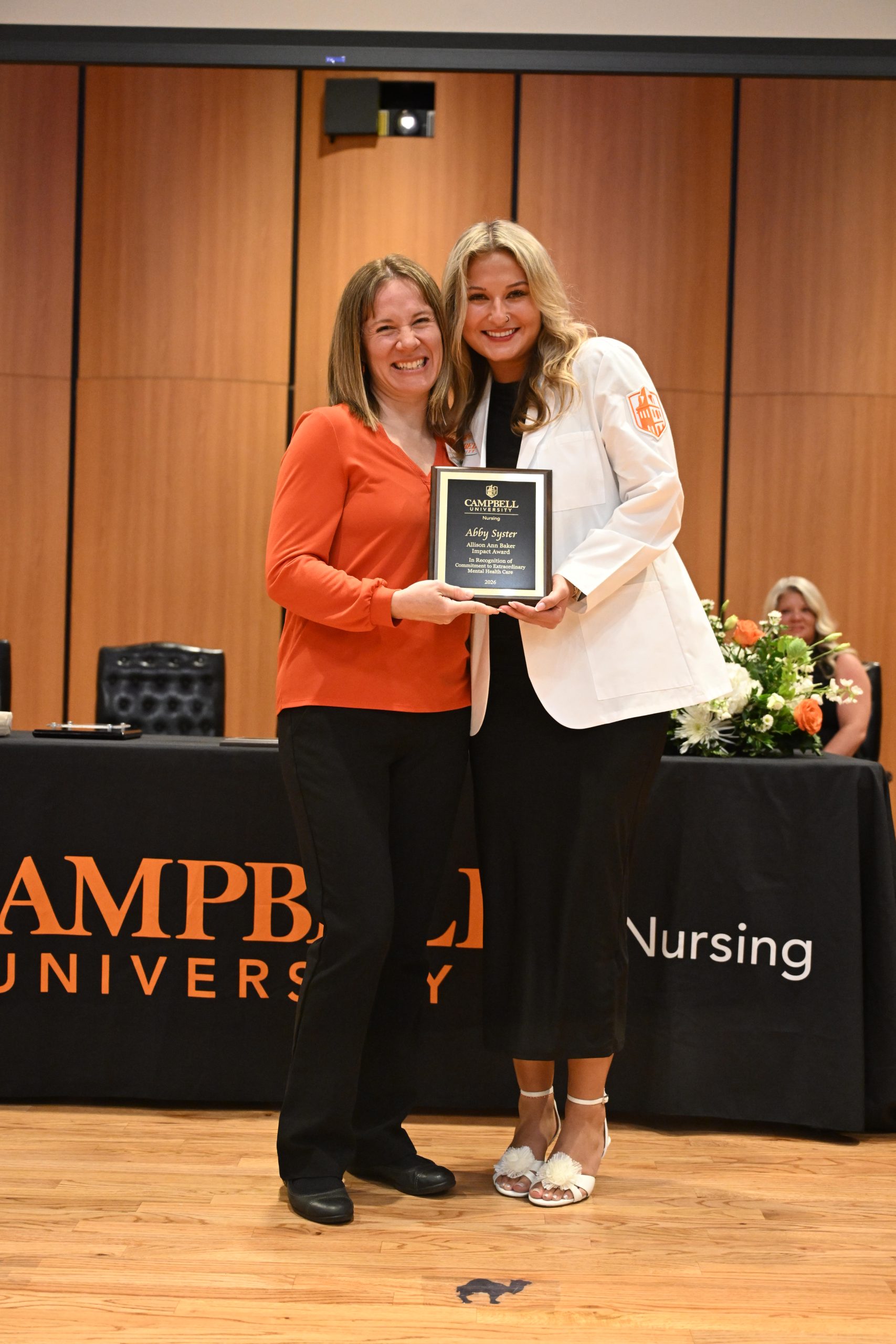 Female faculty and female student holding plaque.