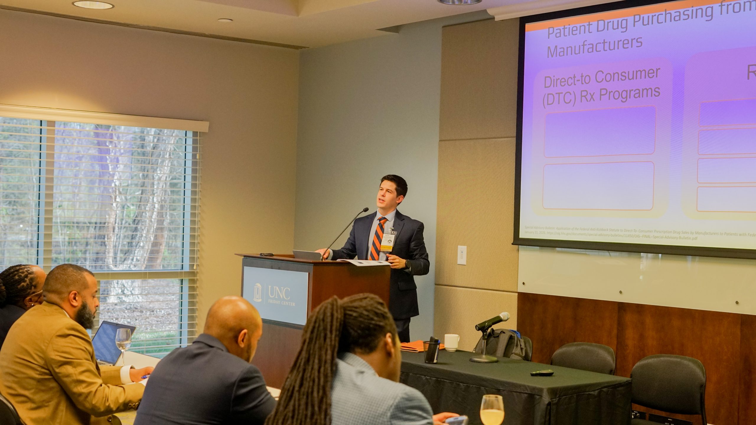Male faculty member speaks to students during conference.