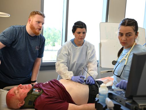 Two female PA students and one PA alumnus using an ultrasound machine