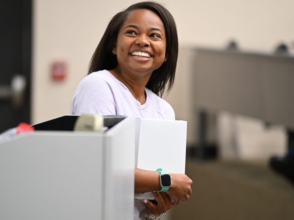 Female student holding award and looking up at screen behind her.