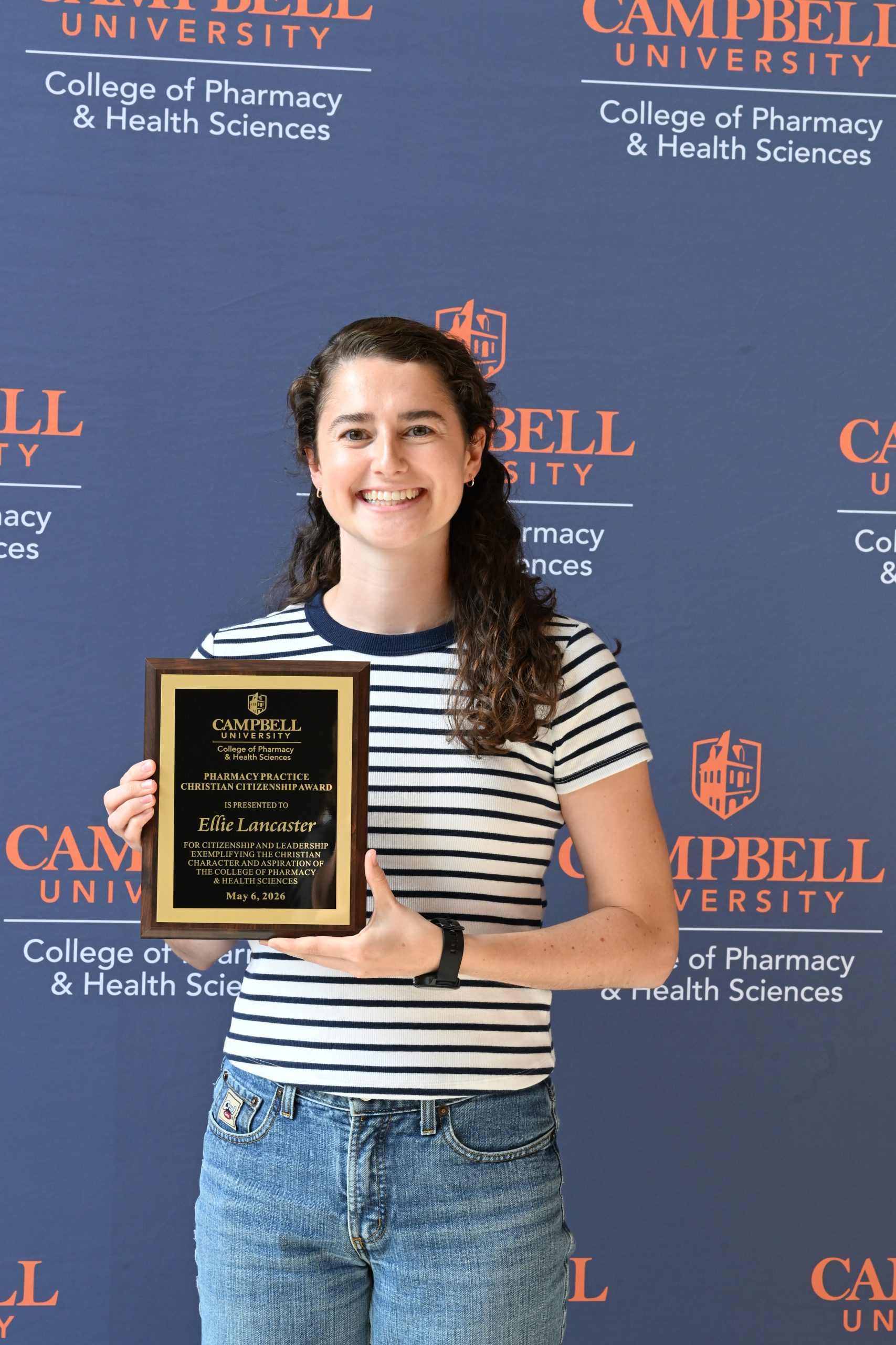 Female holding award plaque.