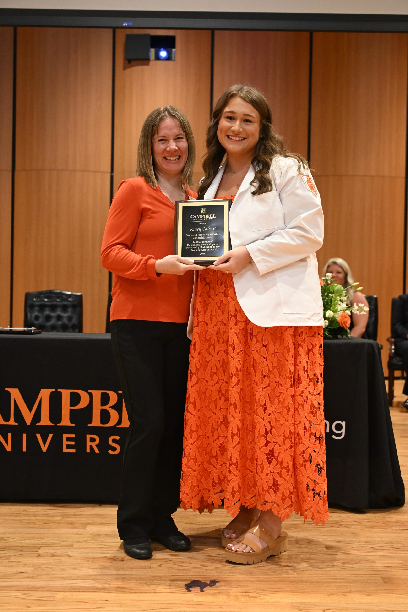 Female faculty and student standing holding plaque.