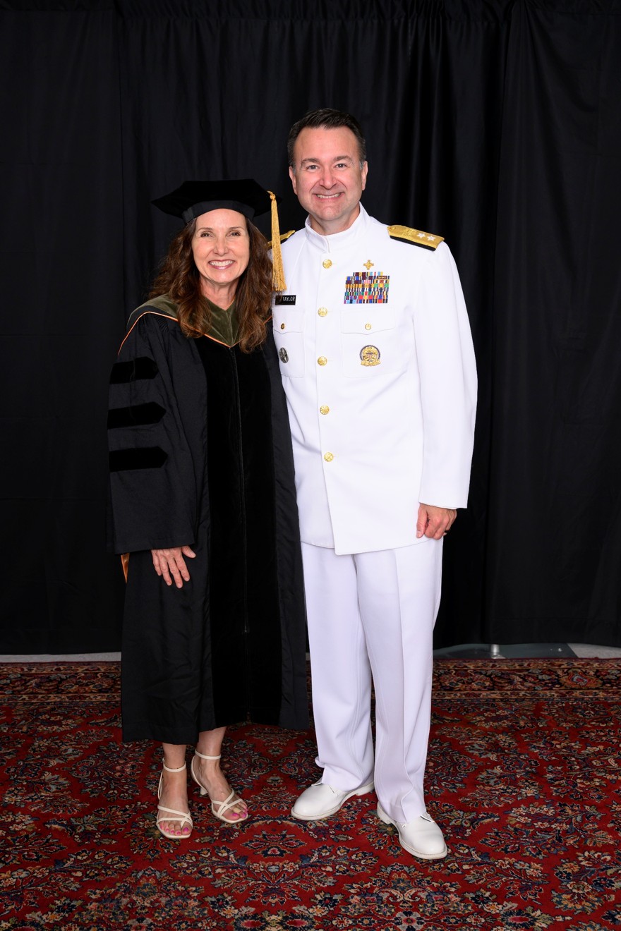 Female in regalia standing beside male in white military uniform