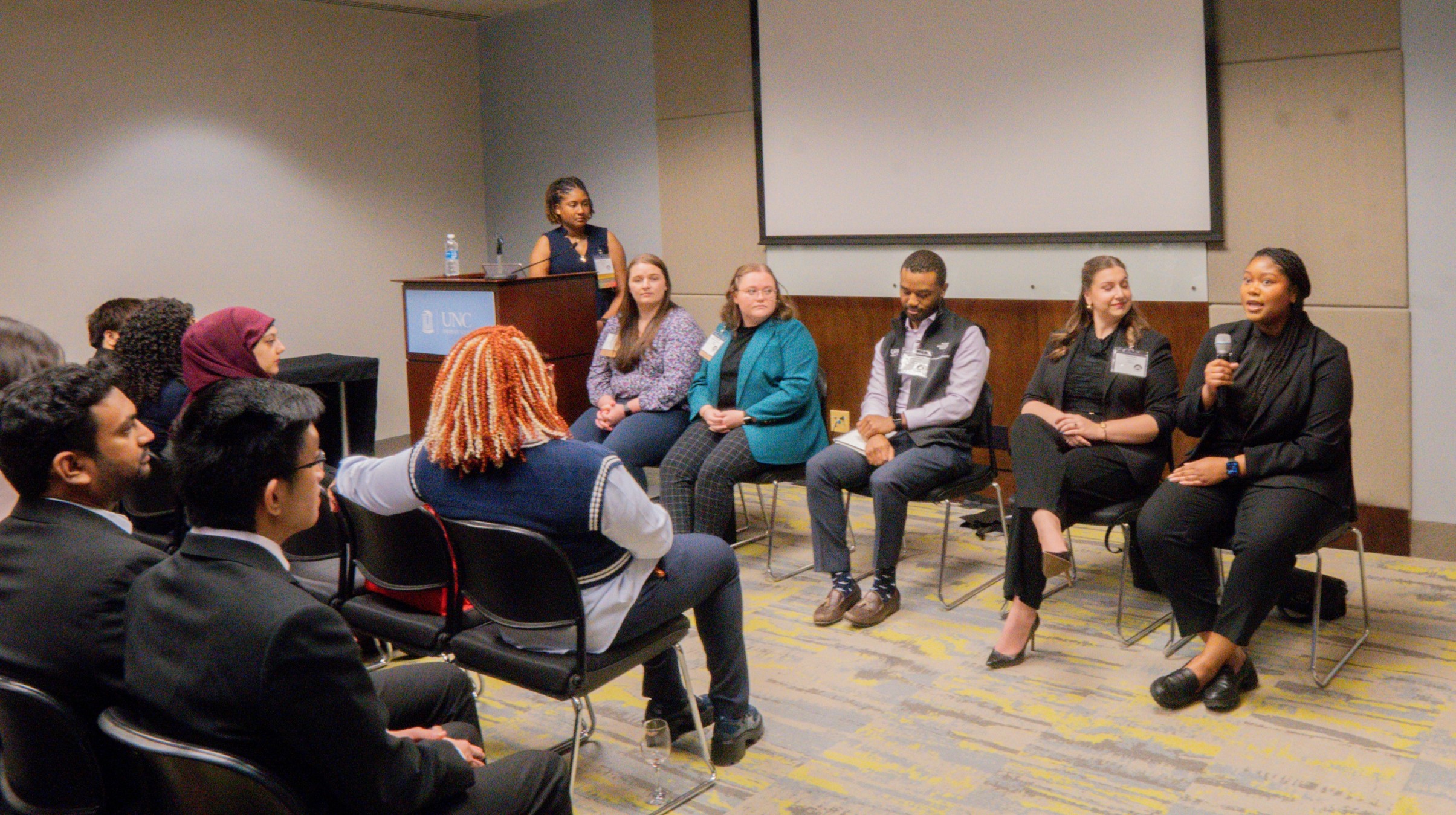 Males and females in a panel with attendees seated in rows.