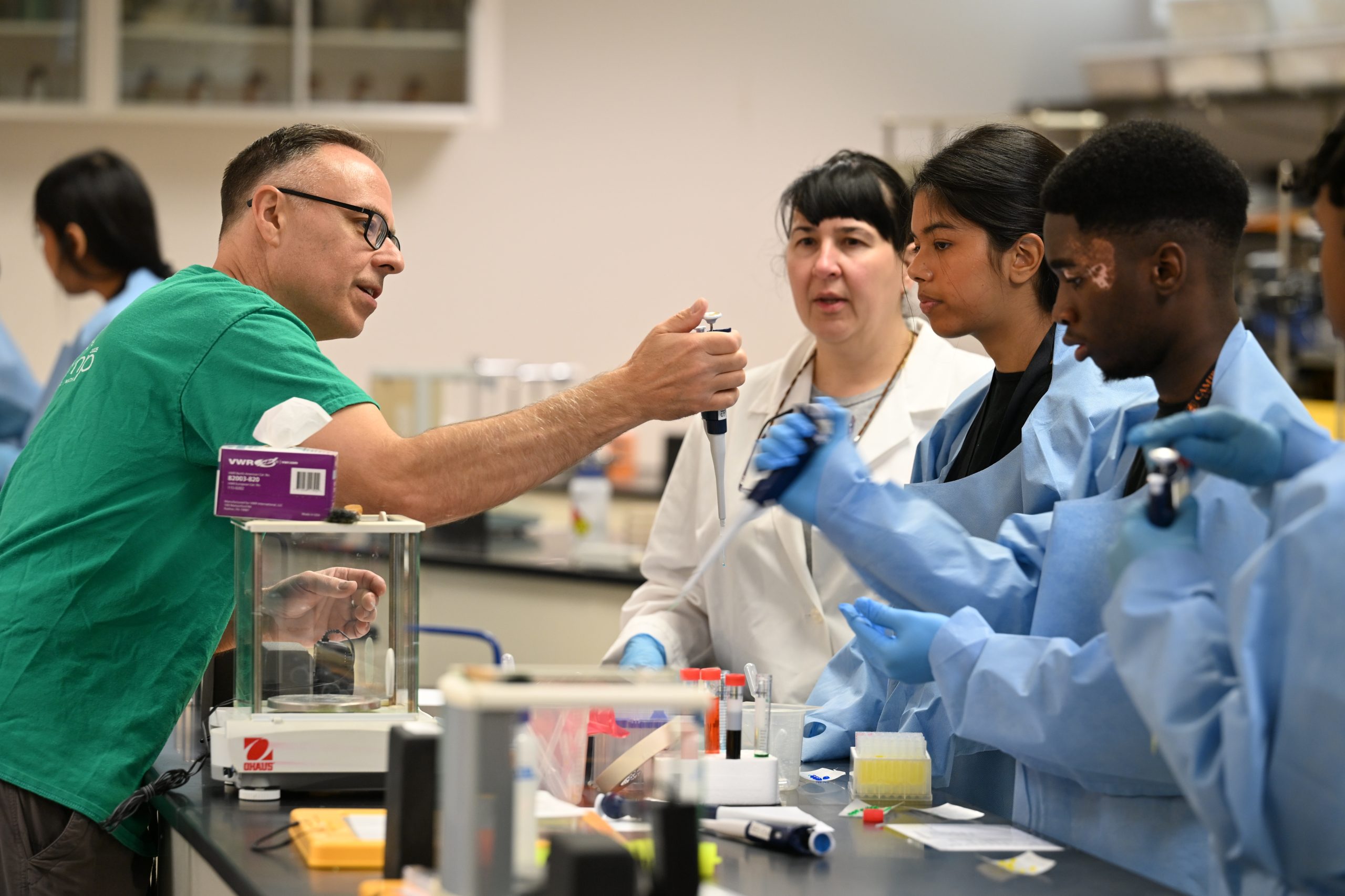 Male faculty member helps students in lab