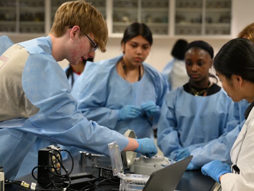 Students in blue PPE watch a demonstration