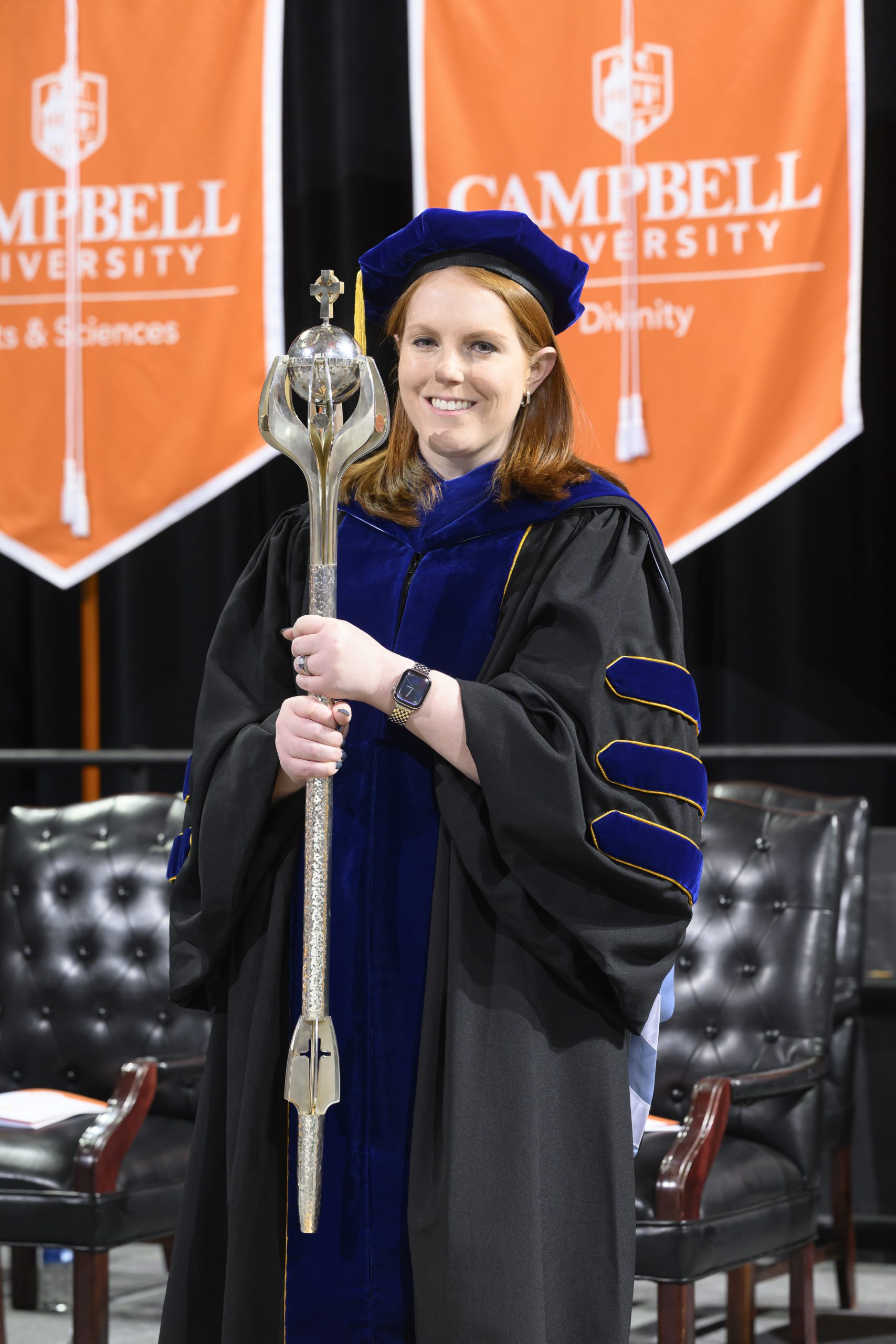Female in regalia holding the University mace.