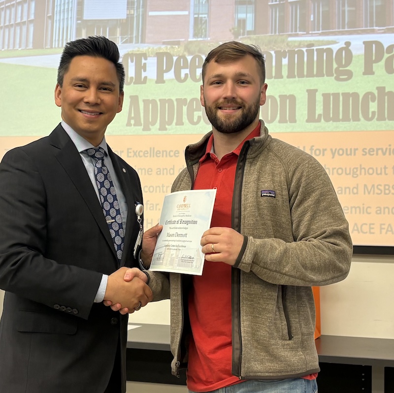 Dr. Tolentino poses with a student holding Peer Learning Partner award.