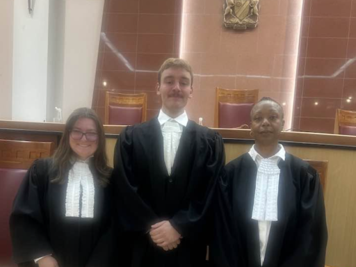 Photo of Campbell Law students Angelena Antenuci ‘27, Tracy Harris ‘27 and Ryan Hogan ‘28 posing in the Namibia high court in their judicial robes.