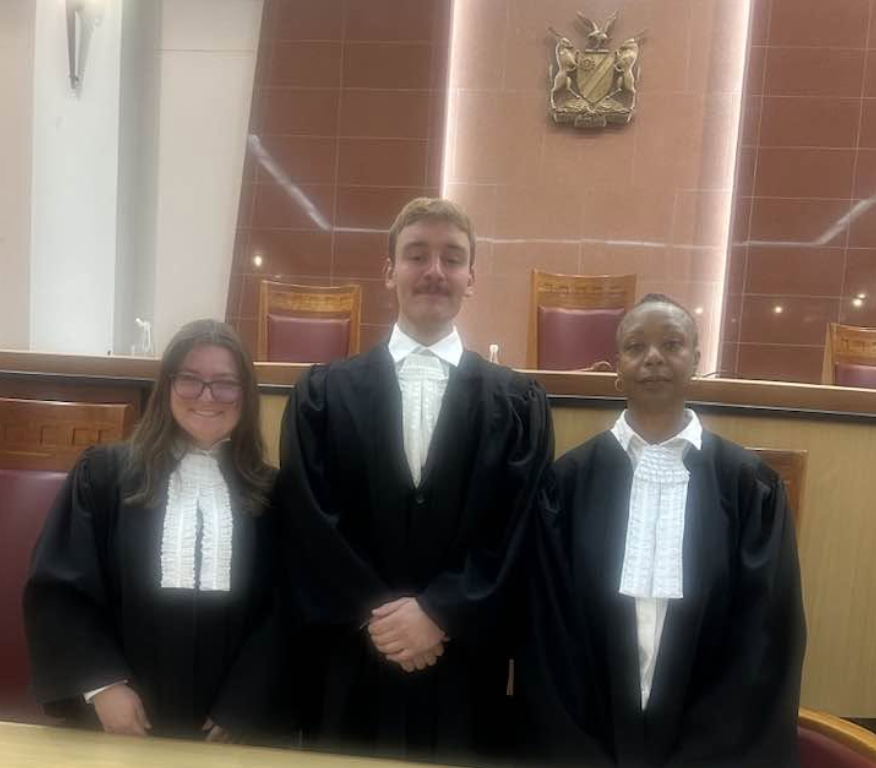 Photo of Campbell Law students Angelena Antenuci ‘27, Tracy Harris ‘27 and Ryan Hogan ‘28 posing in the Namibia high court in their judicial robes.