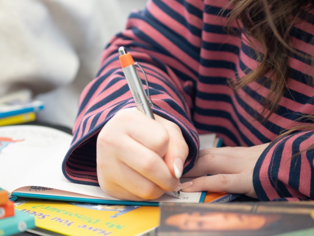 student writing on table with marker