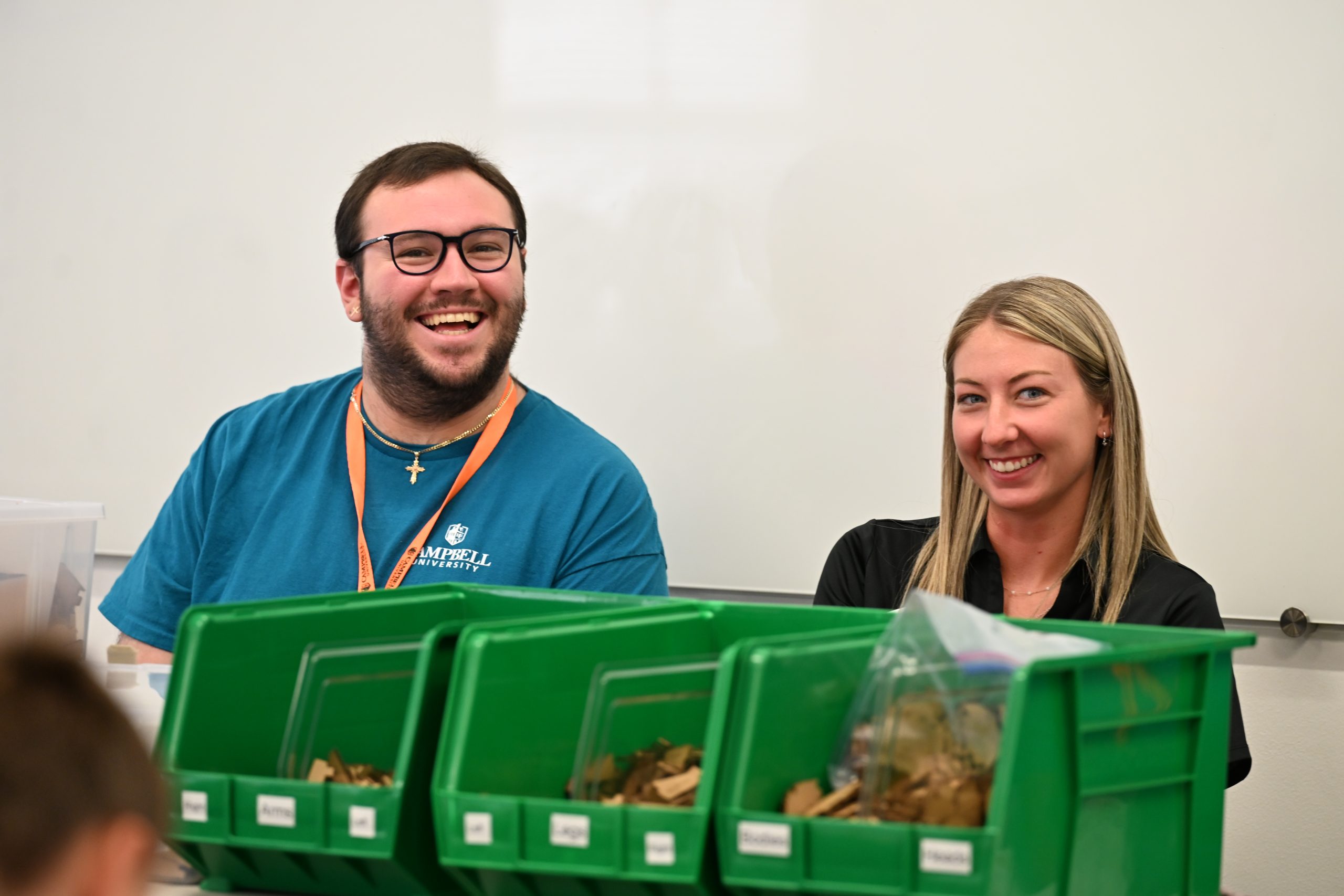 Two Campbell University student mentors smile while assisting middle school participants during STEM Camp.