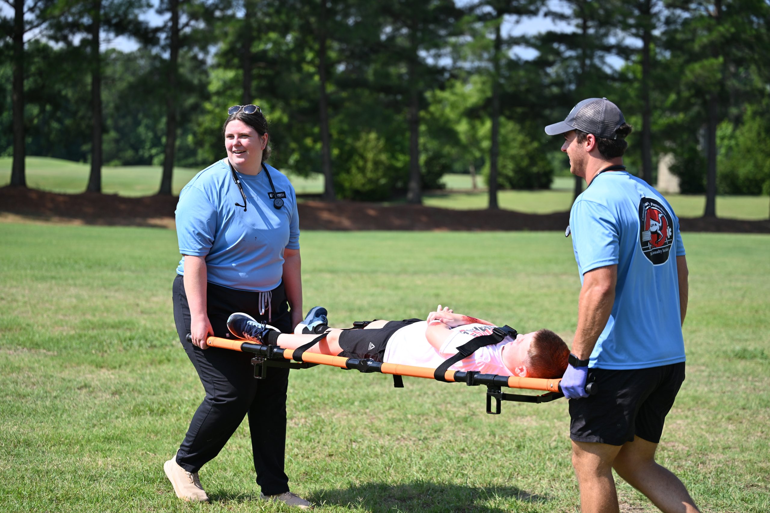 Female and male PA students carrying injured male child on a litter.