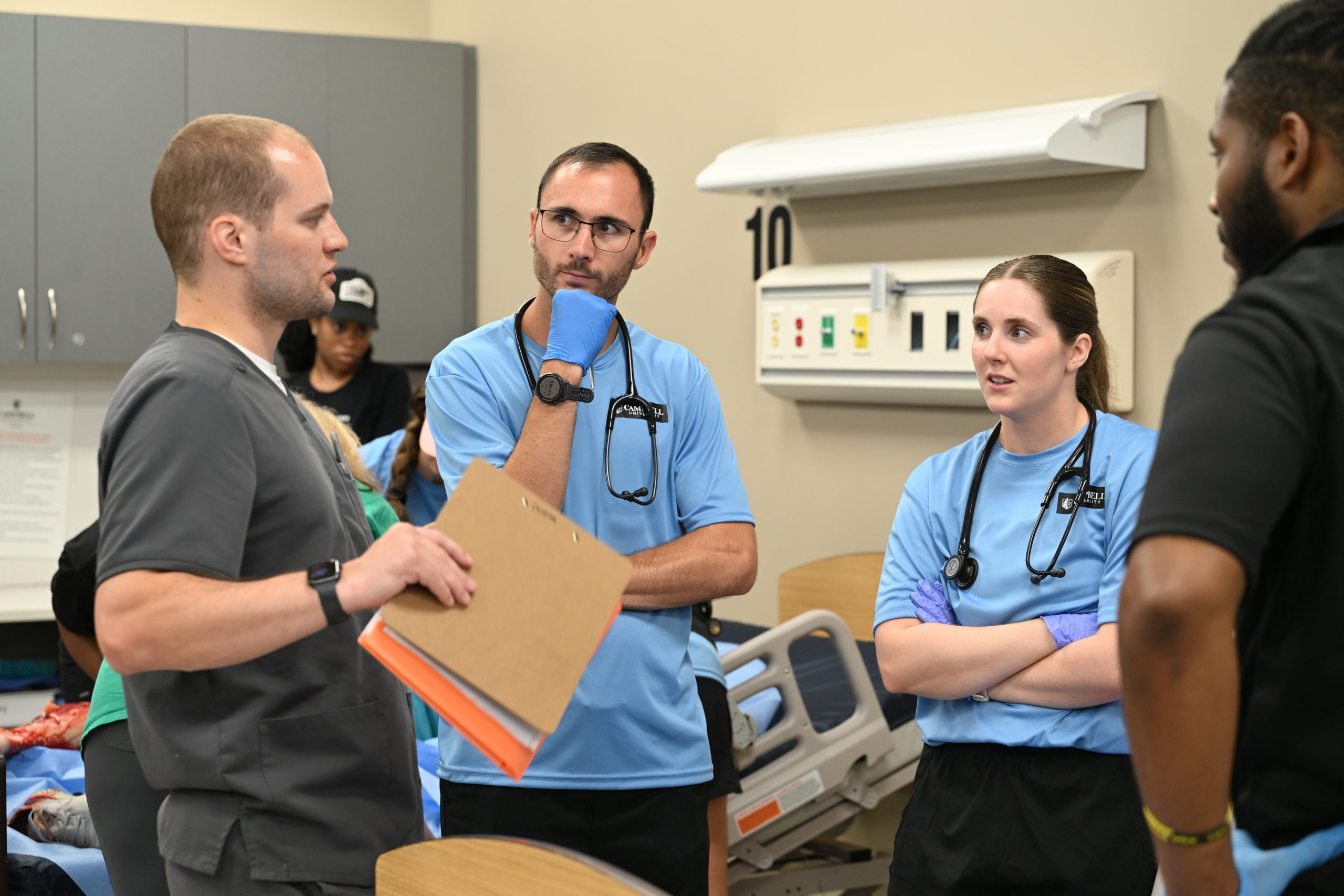 PA students listen to a male alumnus talking to them about procedure in the simulated ER