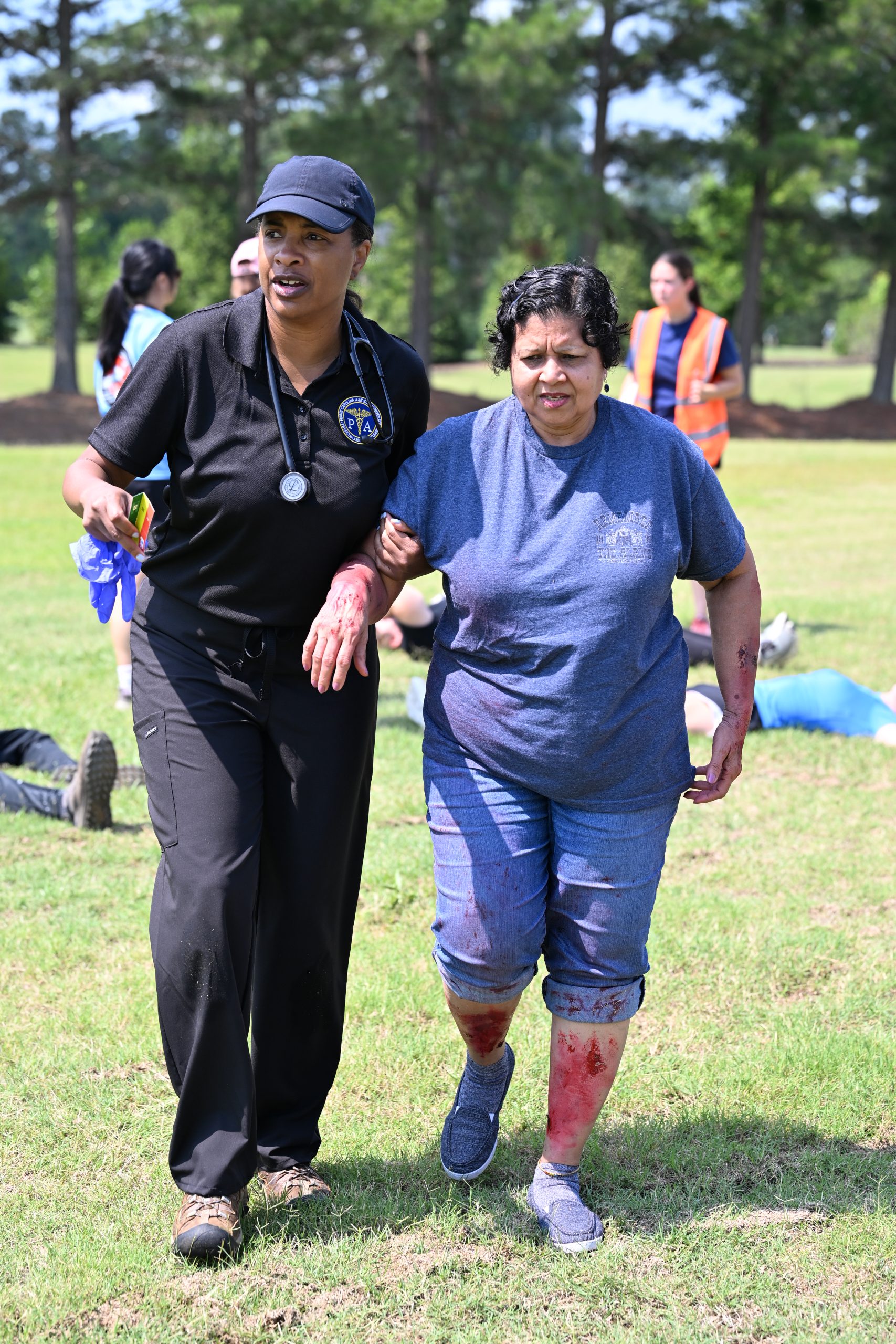 Female student walks with injured patient to a triage tent.