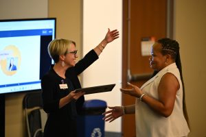 A faculty member presents an award or recognition to an attendee during a ceremony at the Campbell University College of Pharmacy & Health Sciences.