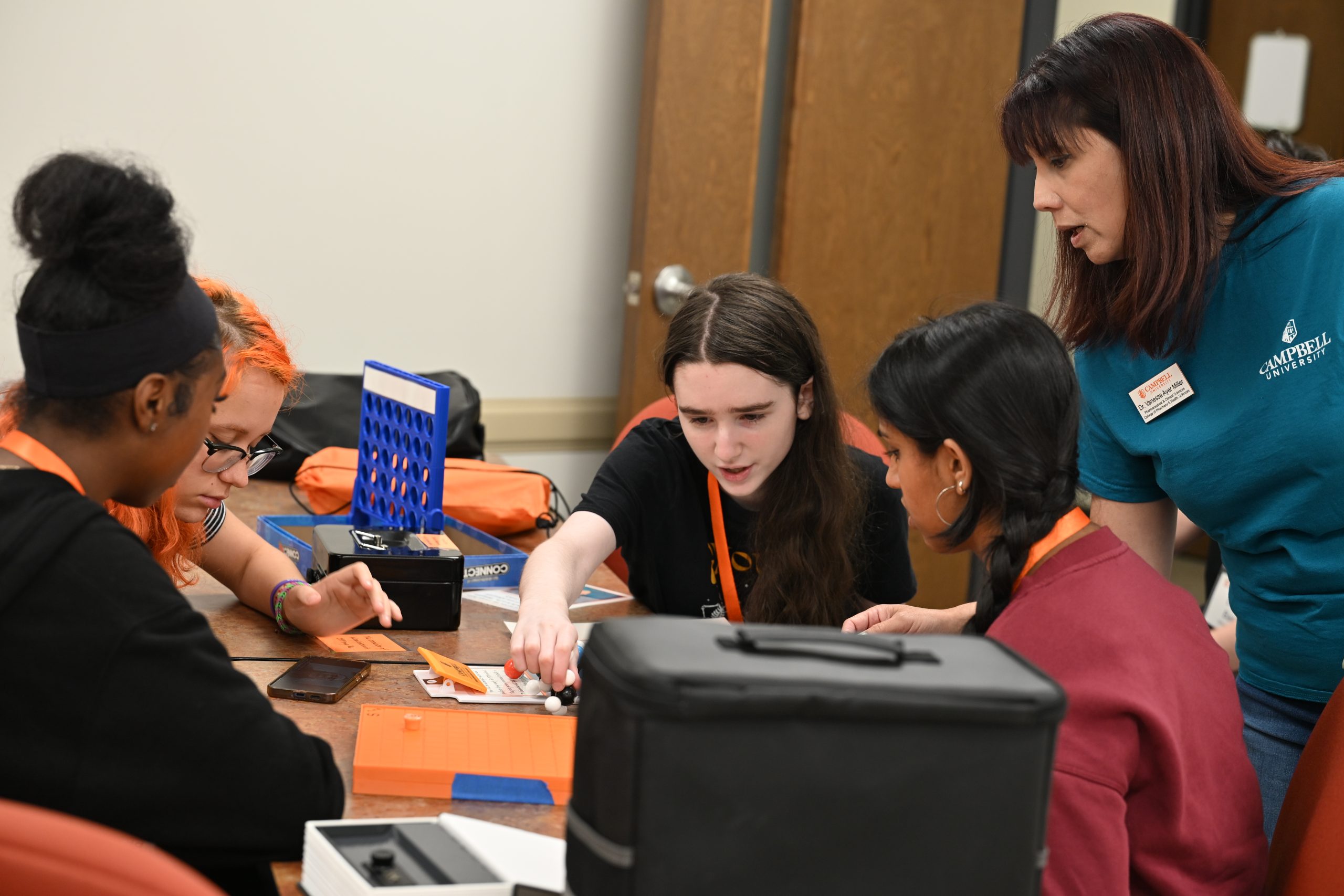 An instructor guides a small group of students as they work together to solve a Clinical Research escape room challenge.