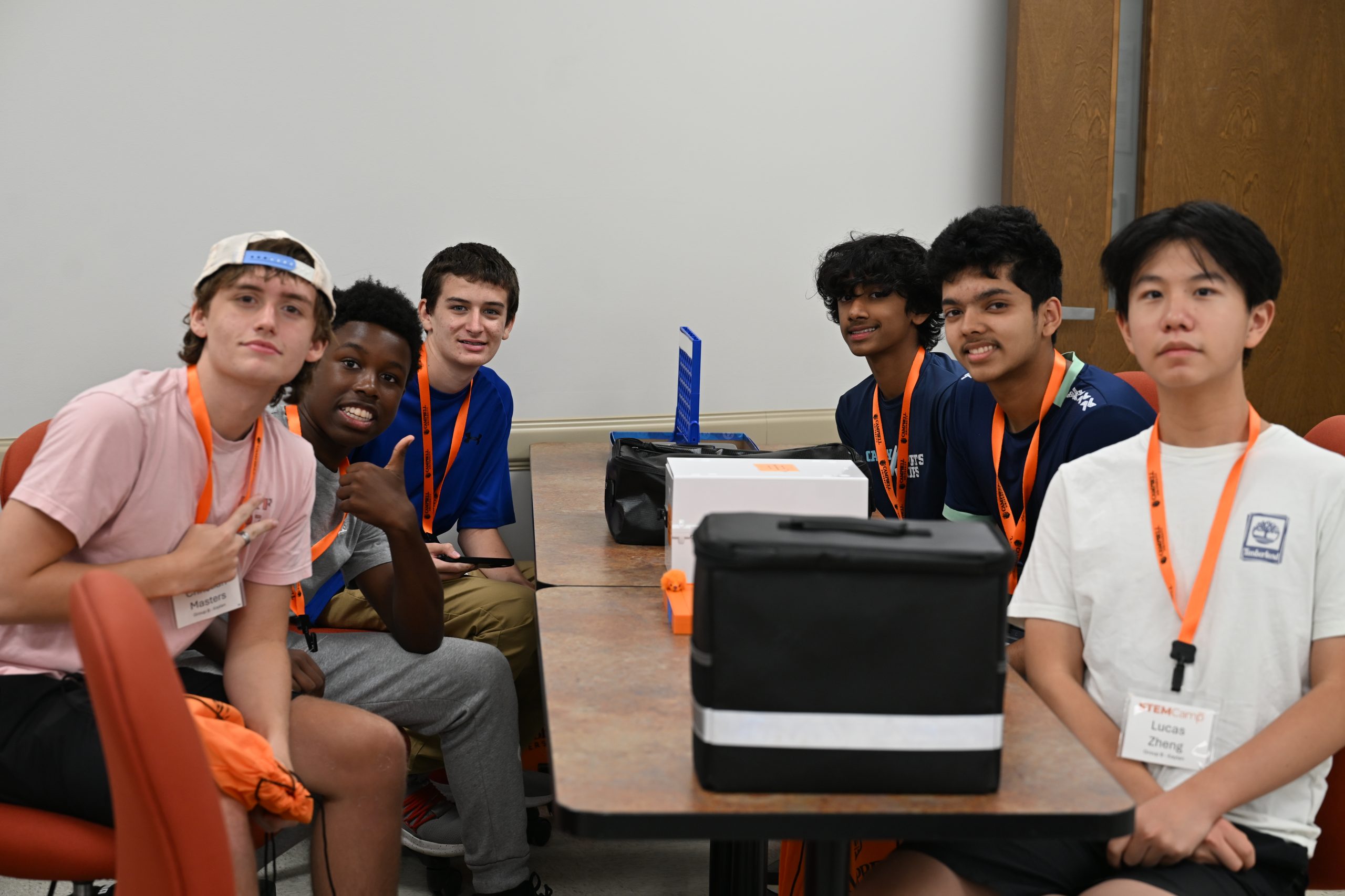 high school STEM Camp participants smile at the camera while seated together before beginning a classroom activity.