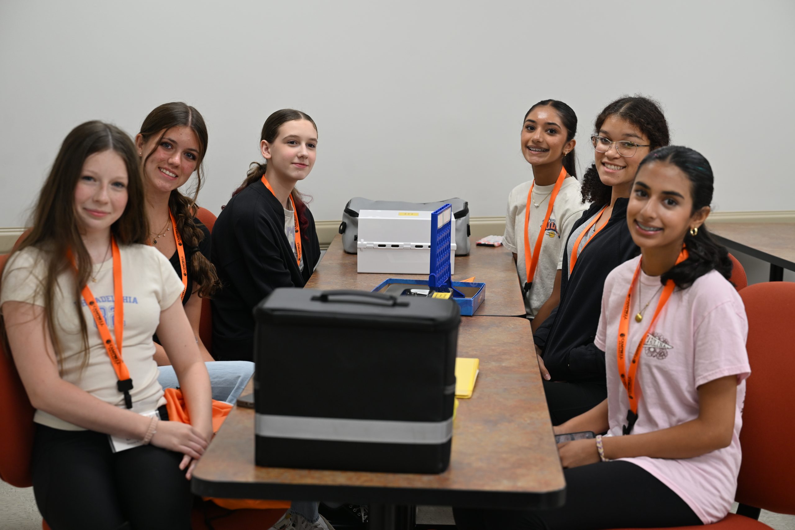 high school STEM Camp participants smile at the camera while seated together before beginning a classroom activity.