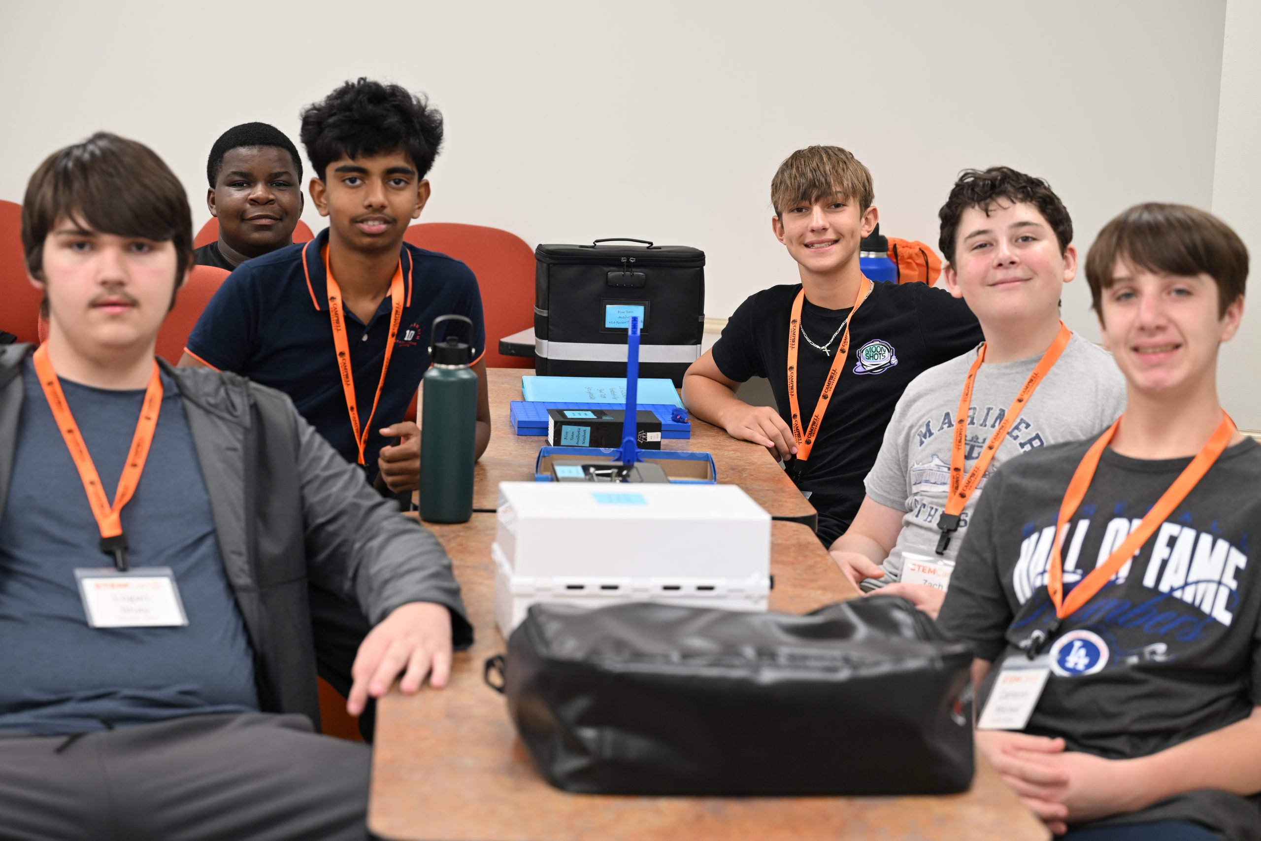 high school STEM Camp participants smile at the camera while seated together before beginning a classroom activity.
