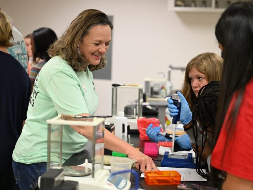 Faculty member provides instruction as students use micropipettes and laboratory equipment to complete a hands-on science experiment in the lab.