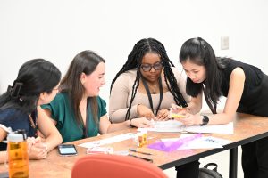 Four students work together around a table, collaborating on a small-group activity during a Campbell University College of Pharmacy & Health Sciences program.