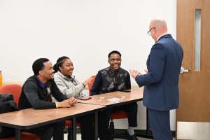 A faculty member engages three students in discussion during a small-group session at a Campbell University College of Pharmacy & Health Sciences program.