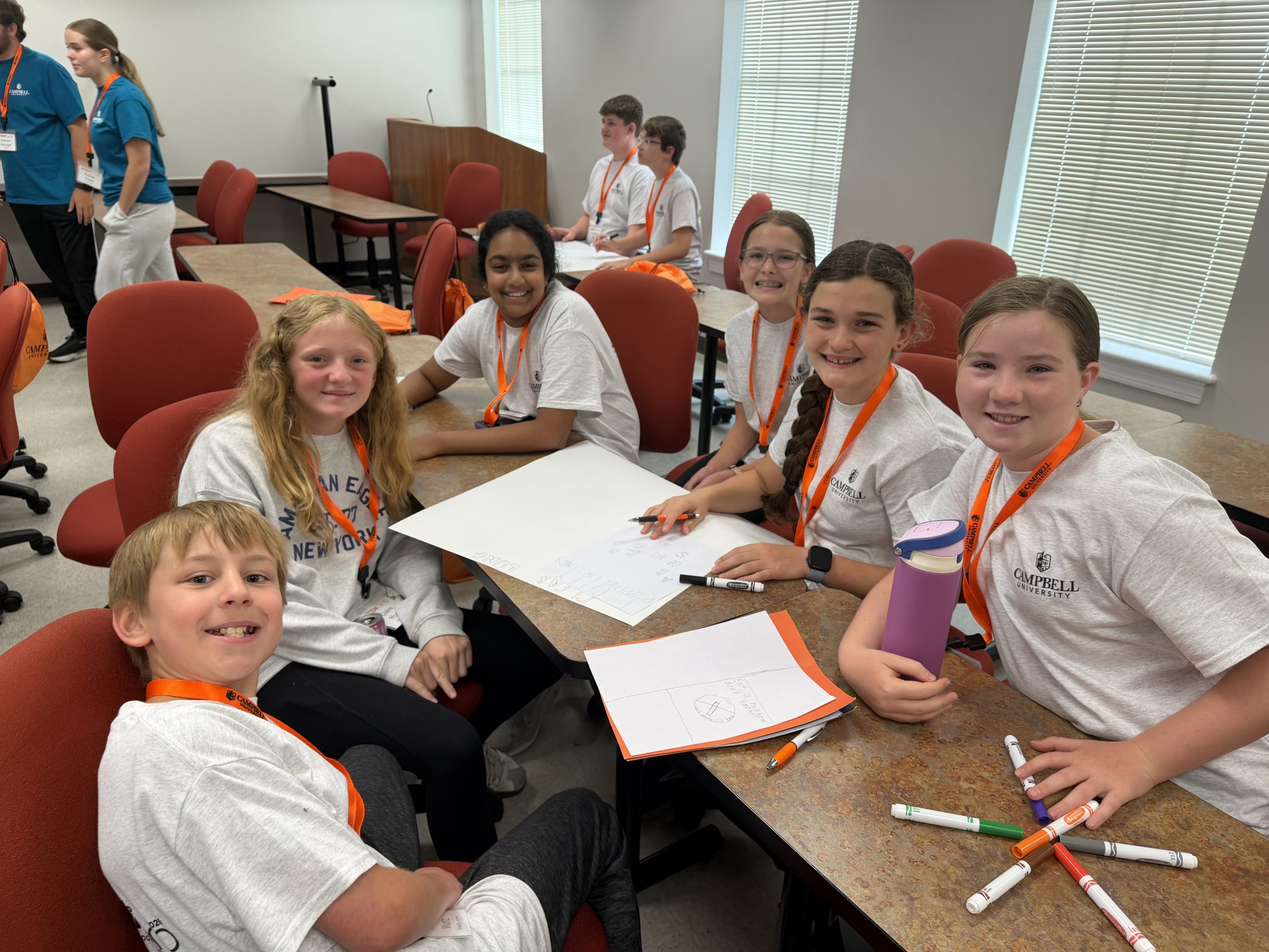 Middle school STEM Camp participants collaborate on a group poster during a hands-on classroom activity.
