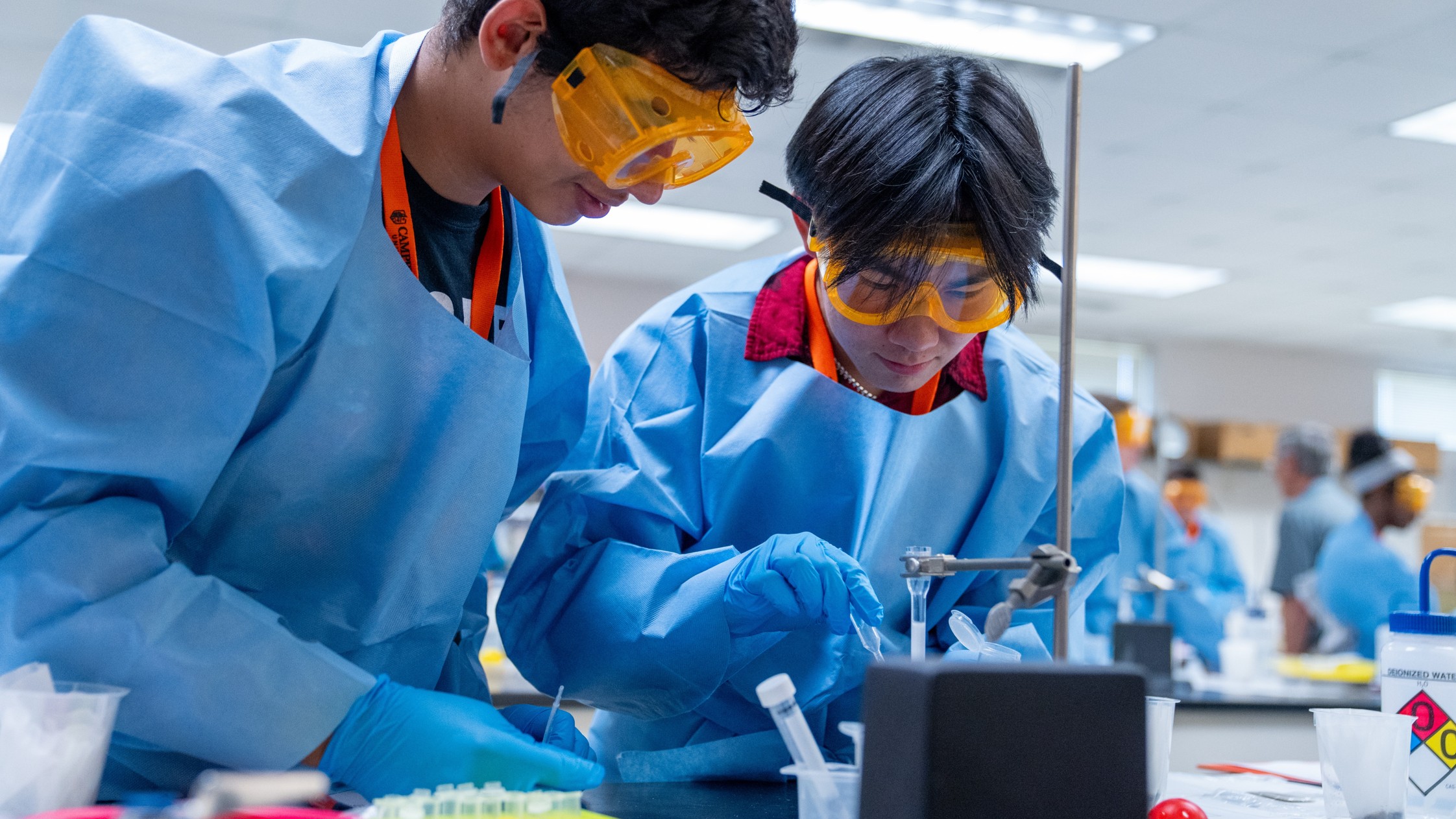 Two STEM Camp participants work together on a laboratory assignment while wearing protective equipment.
