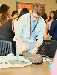 A student practices inserting an intravenous (IV) catheter into a simulation training arm during a healthcare skills lab.