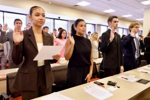 Photo of four first-year law students holding up their right hands as they take the Professionalism Oath during Orientation for the Class of 2029
