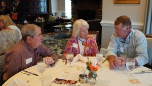 Three Golden Club alumni chatting with each other while seated together at a table during the annual Golden Club Luncheon.
