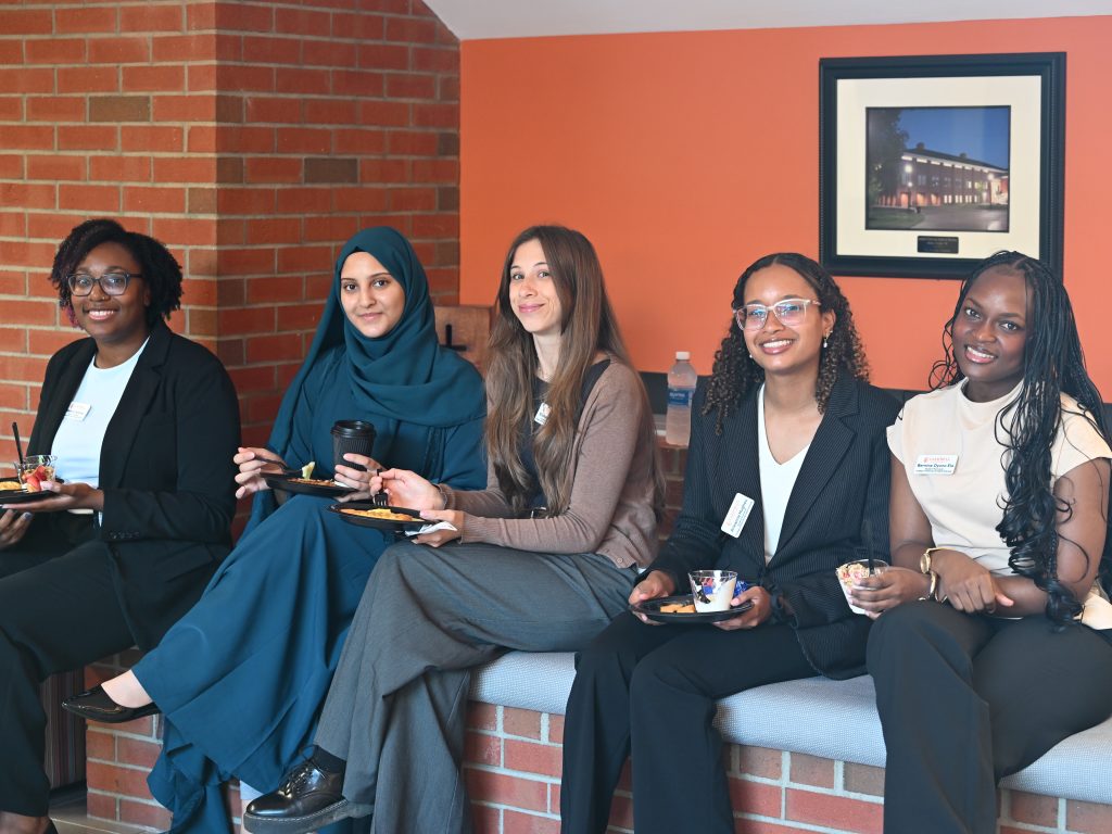 Five female students sitting together enjoying a light breakfast