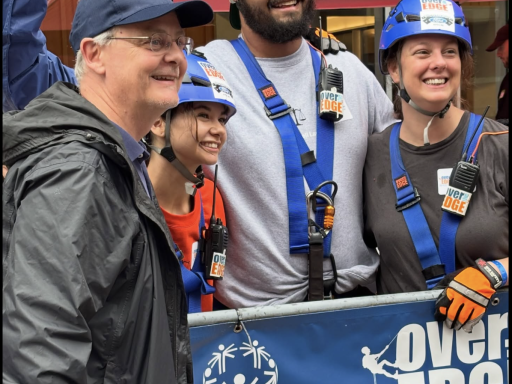 Photo of three Campbell Law students dressed in harnesses with a man from Special Olympics ready to go 'Over the Edge' for Special Olympics in 2025
