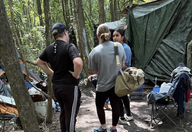 Students talking at an encampment in the woods.
