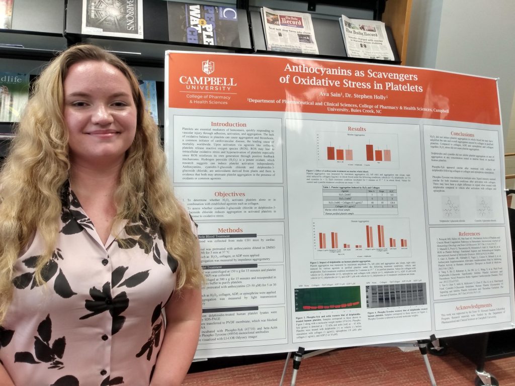 Female student standing beside research poster