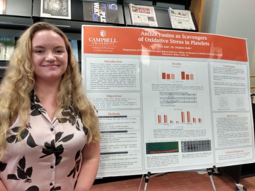 Female student standing beside research poster