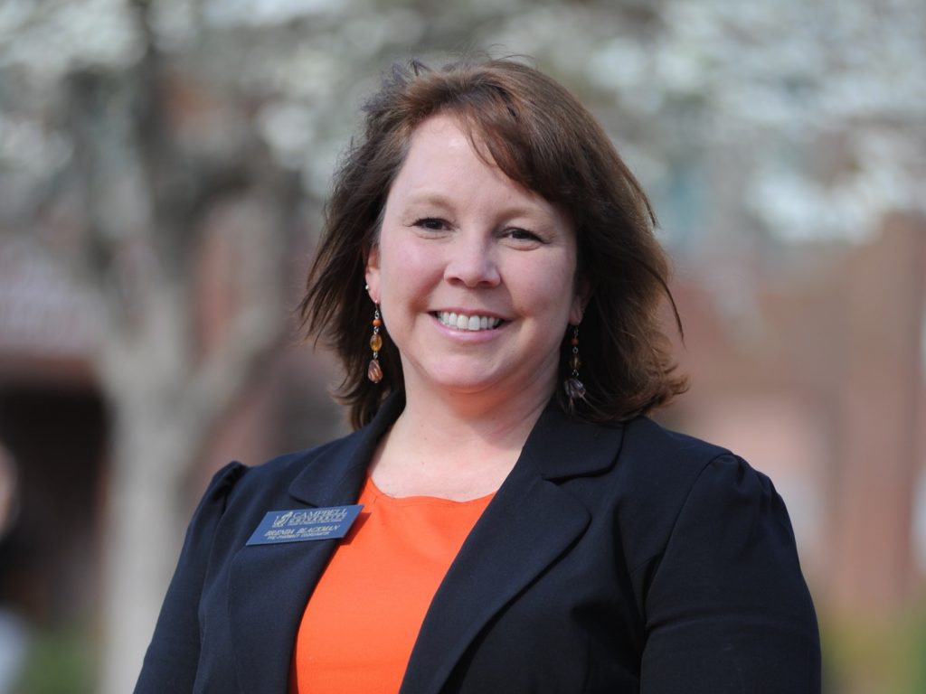 Female in black suit with orange blouse standing outside