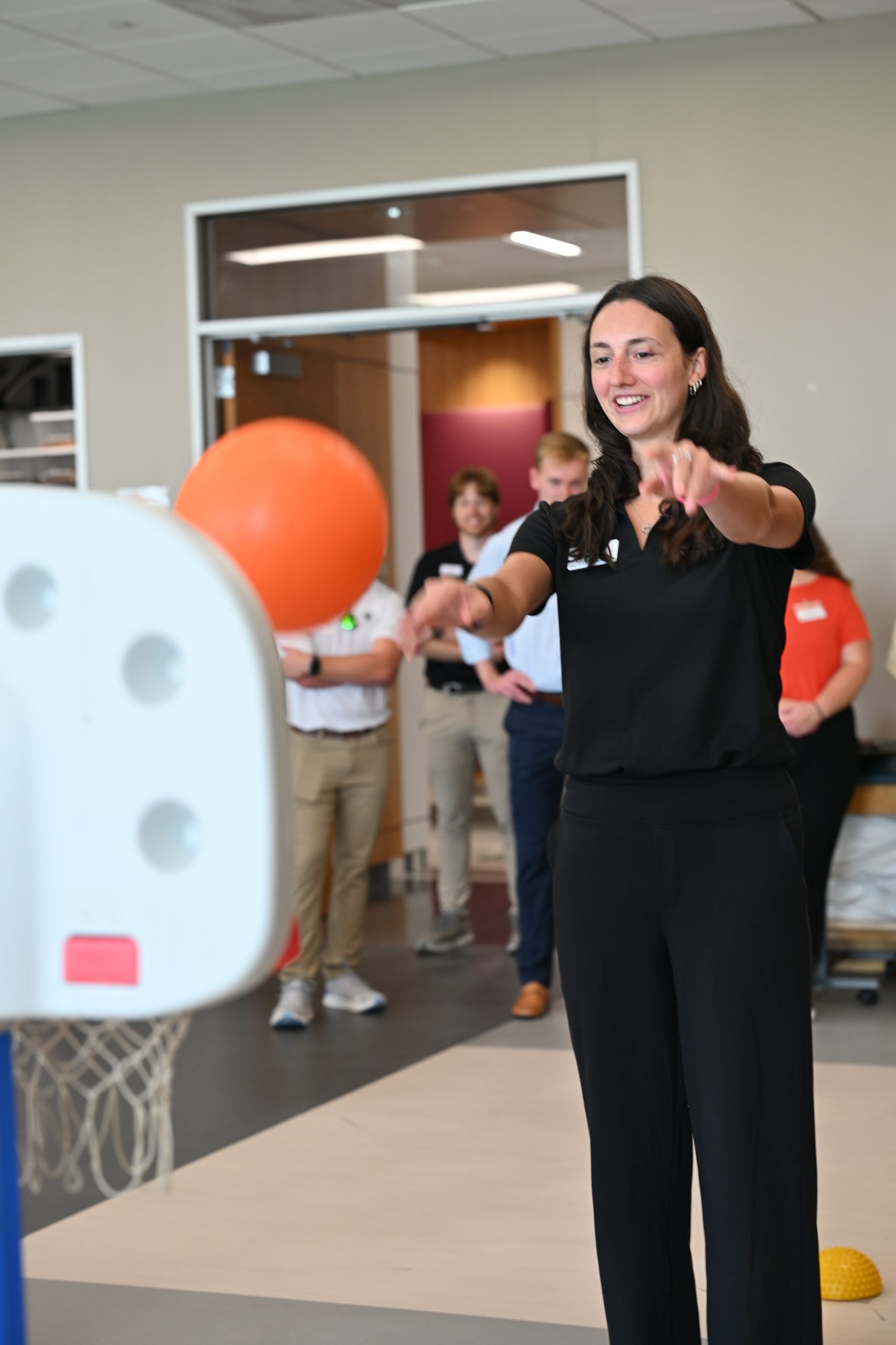 Student throwing a small rubber ball into a toy basketball goal