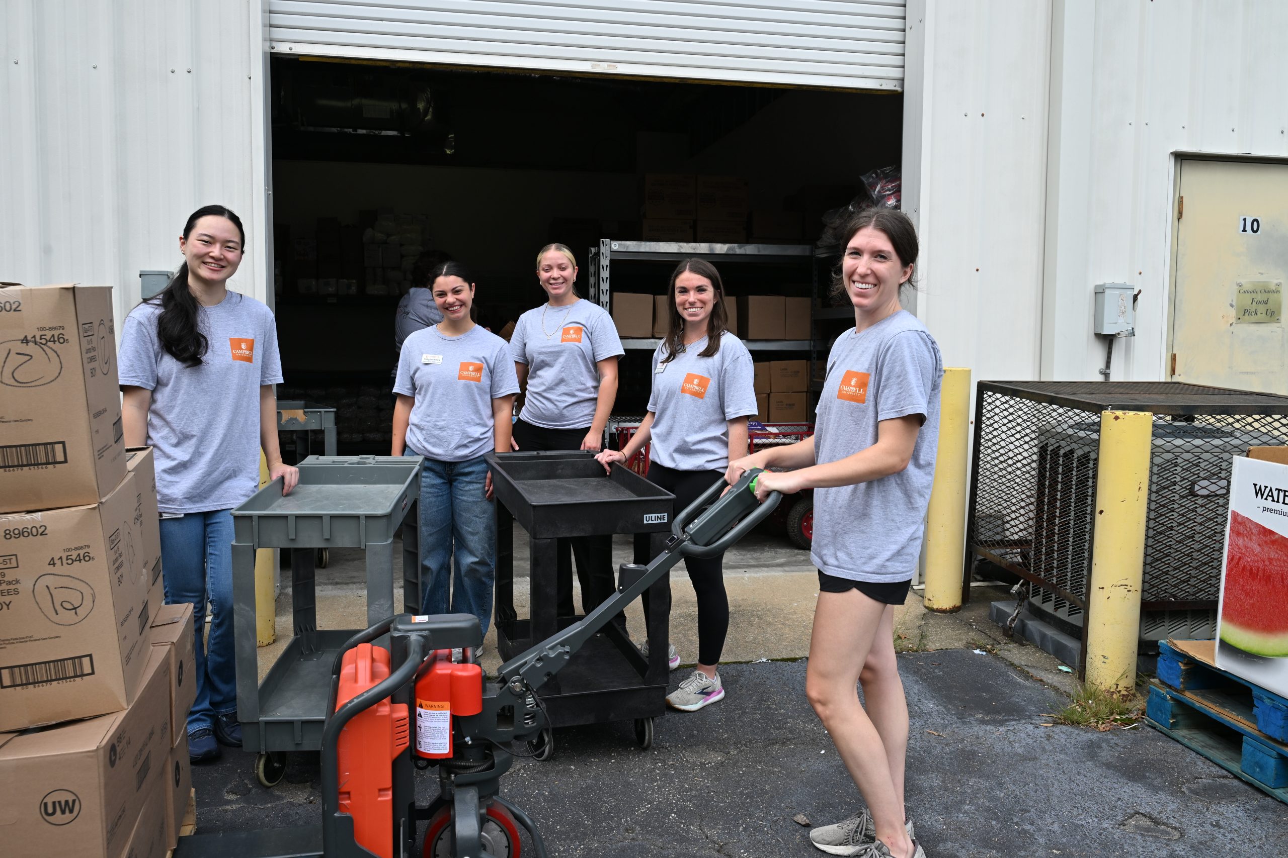 Group of students outside a storage area with carts.