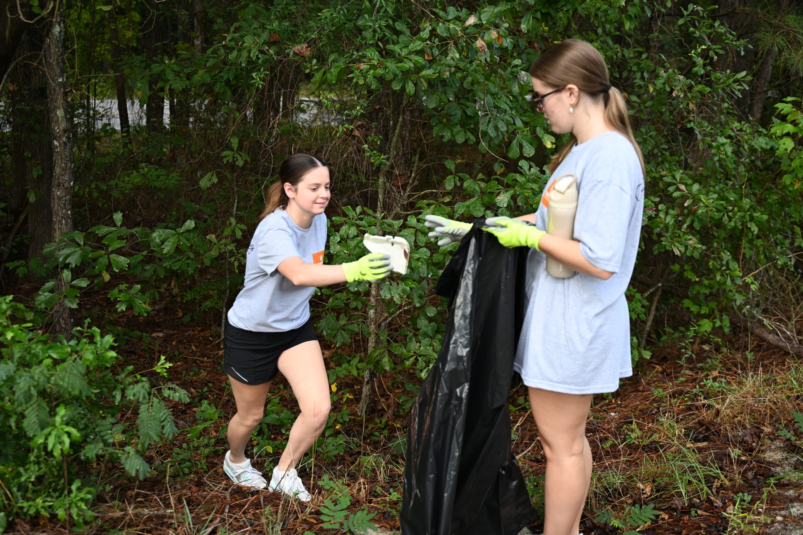Student picking up trash and putting it into a bag.